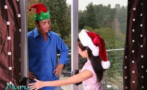 Fully clothed Asian female with crossed legs entertains man at Christmas time