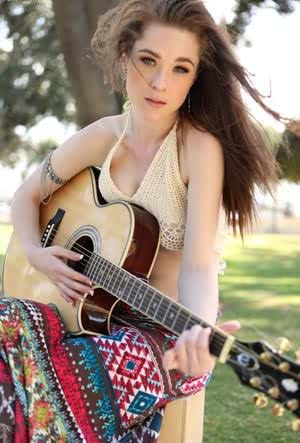 British free spirit Penny Brooks flashes a breast while playing her guitar